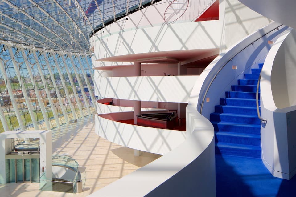 A modern architectural structure with a glass ceiling, blue stairs, and a white exterior.