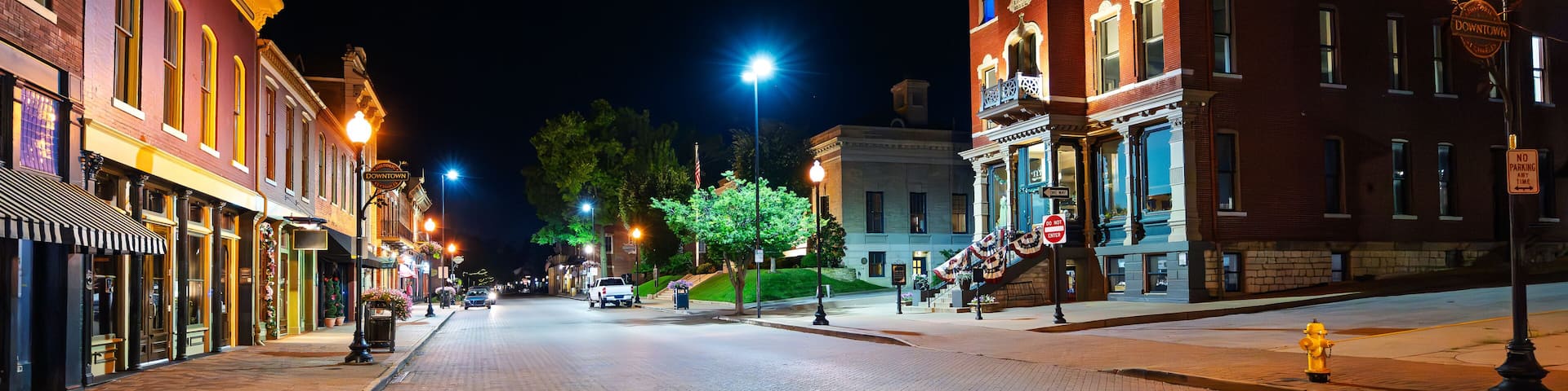 The historic brick paved Main Street with the 1878 Odd Fellows Hall illuminated alongside shops and cafes, in historic St. Charles, Missouri.