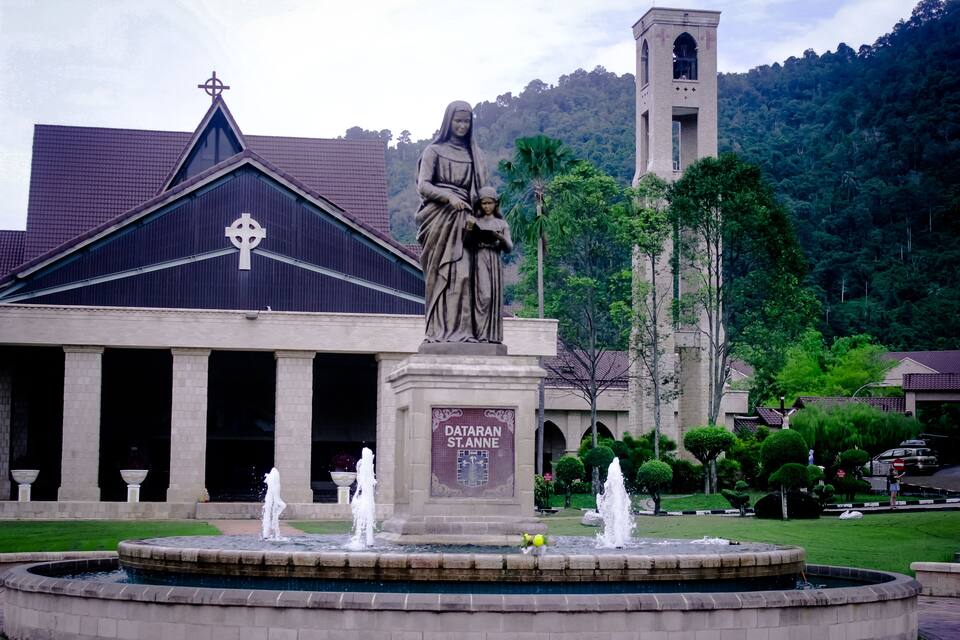 A church with a statue, a fountain, and a tower.