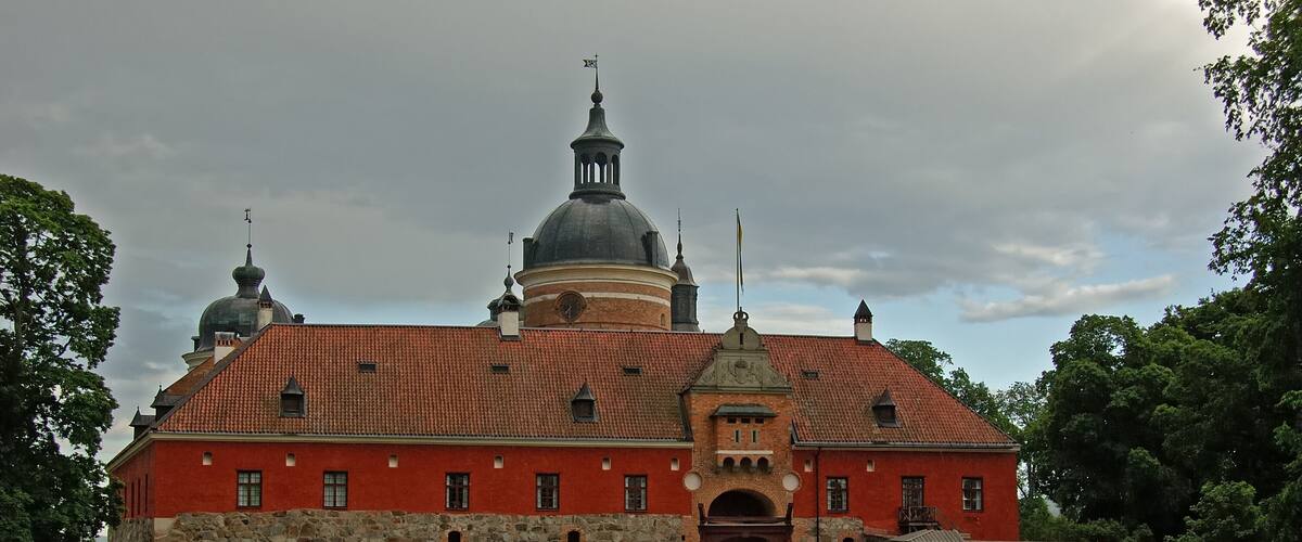 A large red brick building with a stone wall and a dome.
