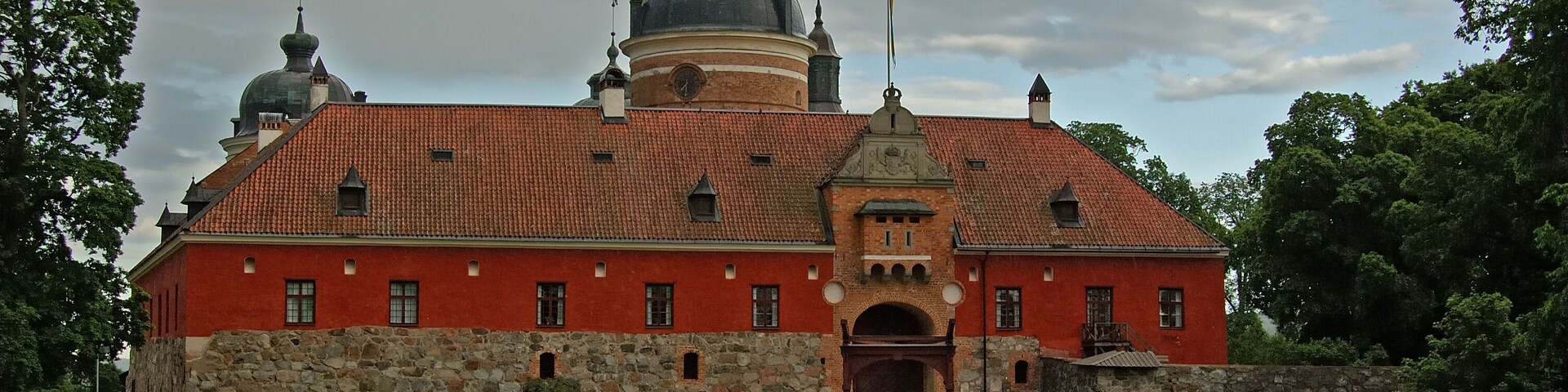 A large red brick building with a stone wall and a dome.