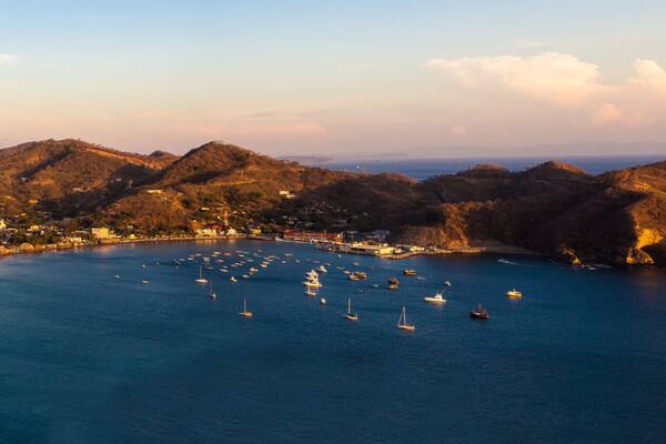 Un pueblo costero con una bahía llena de barcos, rodeado de colinas.