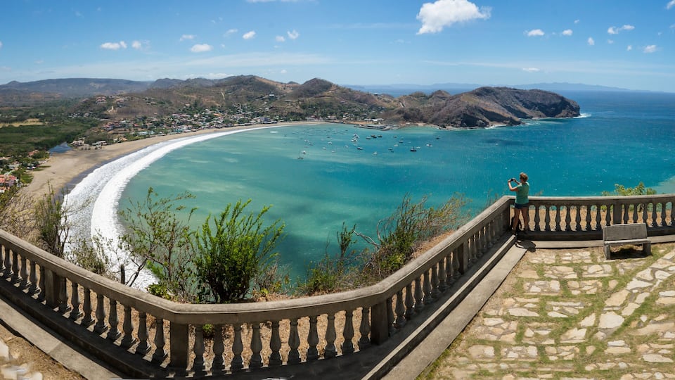 Un paisaje costero con una vista despejada del océano, una playa y montañas al fondo.