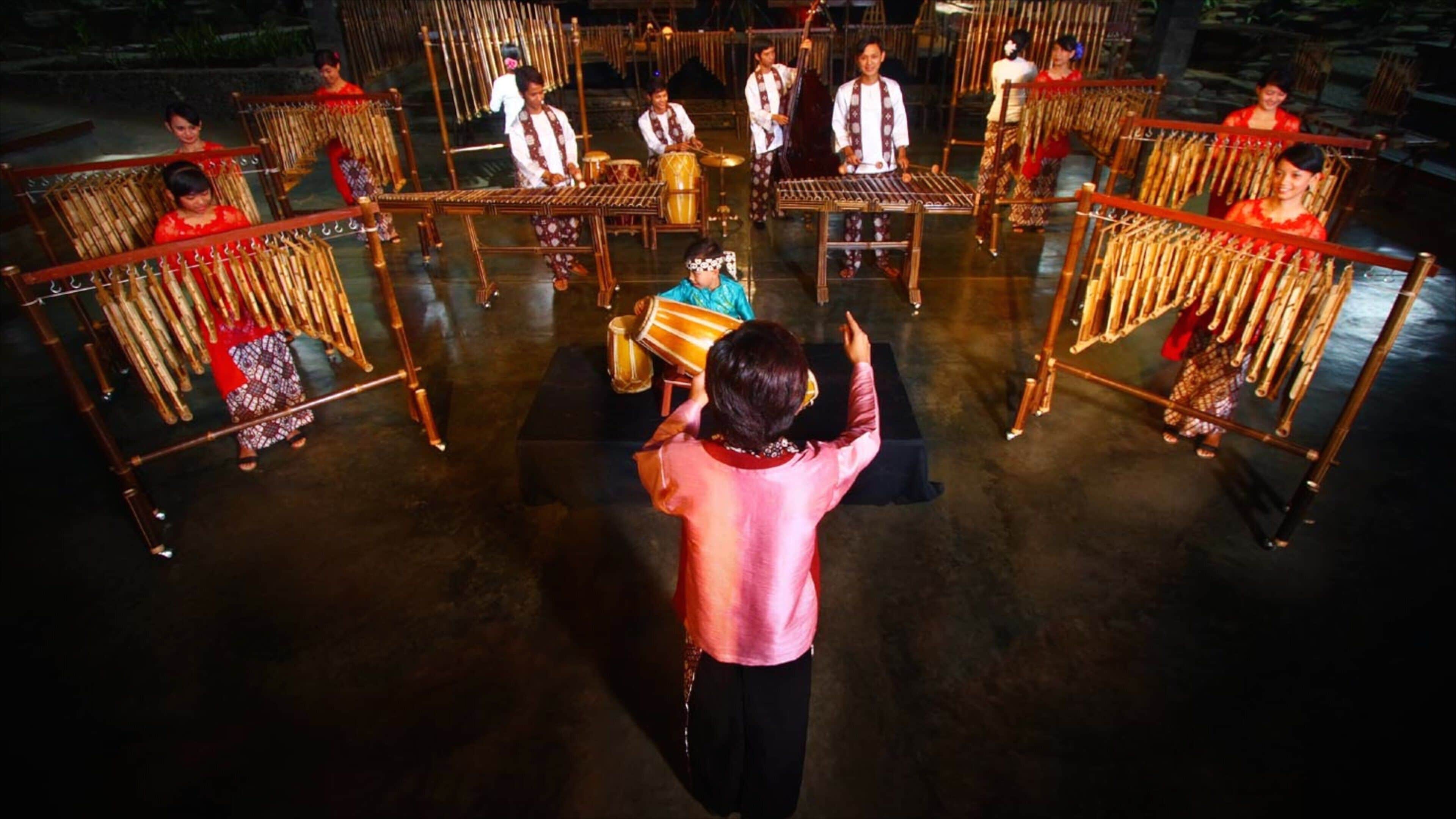 A traditional musical performance with musicians seated on bamboo chairs, playing various instruments.