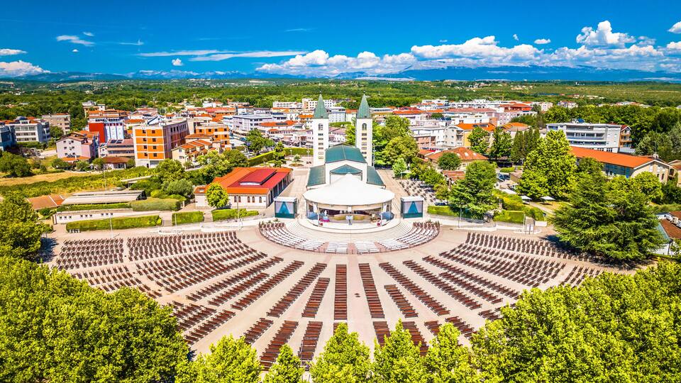 A cityscape with a central round plaza, a prominent church with a green dome, and surrounding residential buildings.