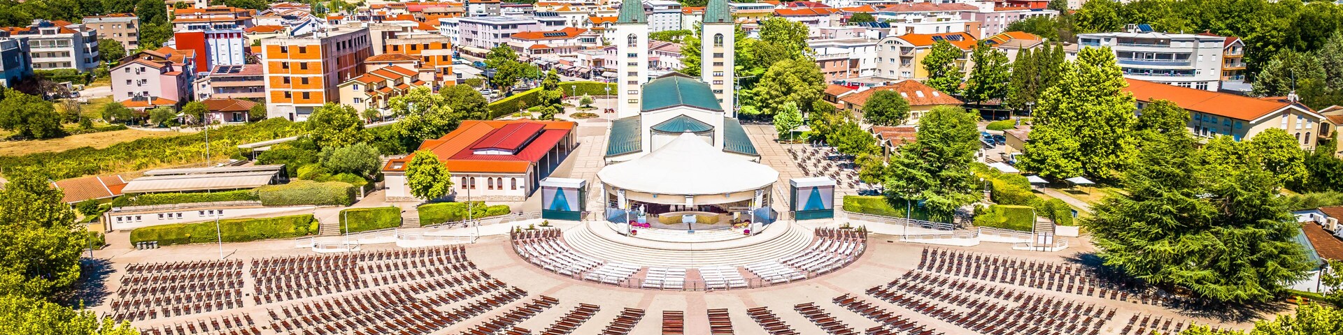 A cityscape with a central round plaza, a prominent church with a green dome, and surrounding residential buildings.