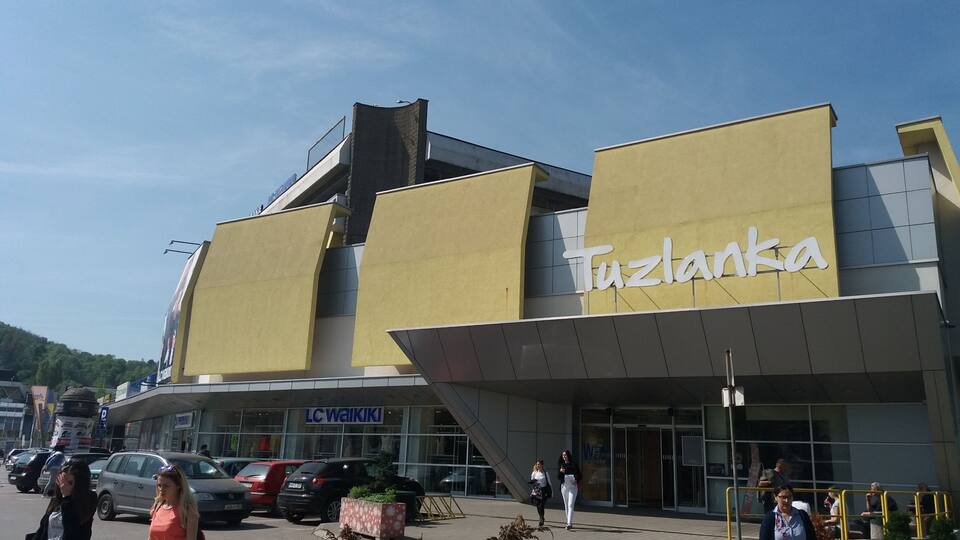 A building with a yellow facade and the name 'Tuzlanka' on it.
