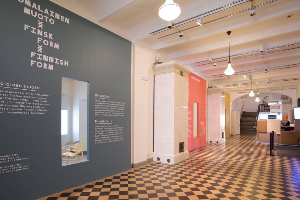 An interior with a checkered floor, a staircase, and informational displays about Finnish and Swedish design.