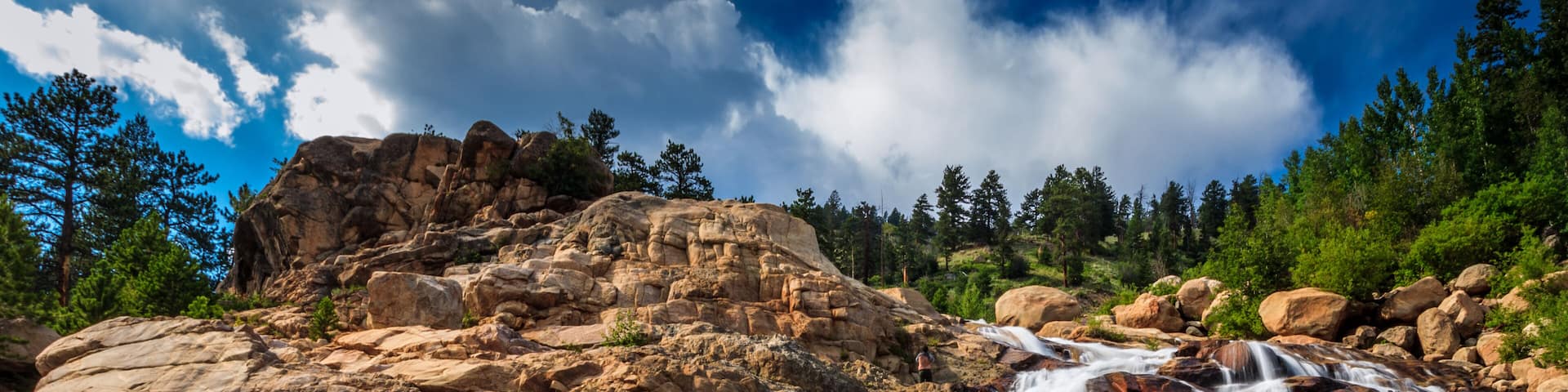 Rocky Mountains national park, glacier waterfall in daylight with clouds.