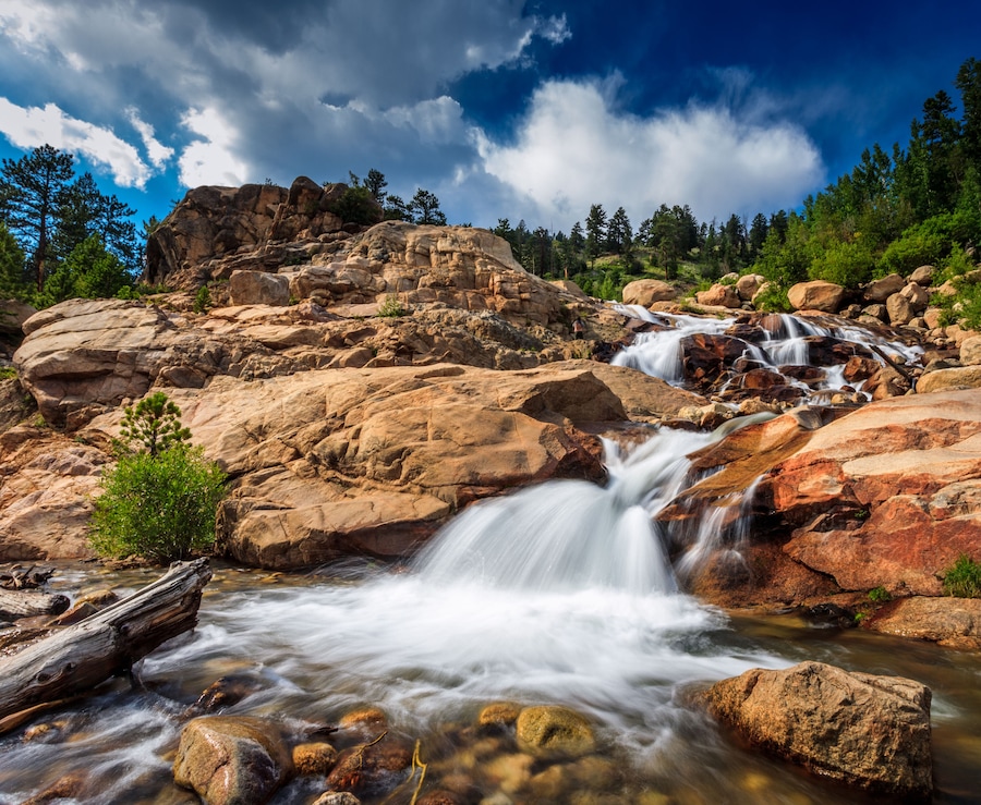 Rocky Mountains national park, glacier waterfall in daylight with clouds.