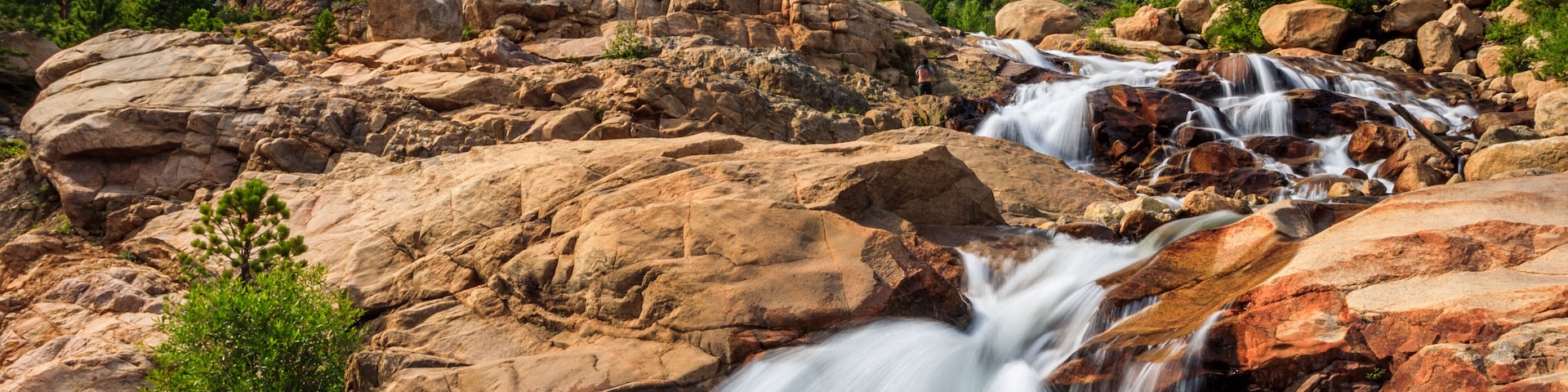 Rocky Mountains national park, glacier waterfall in daylight with clouds.