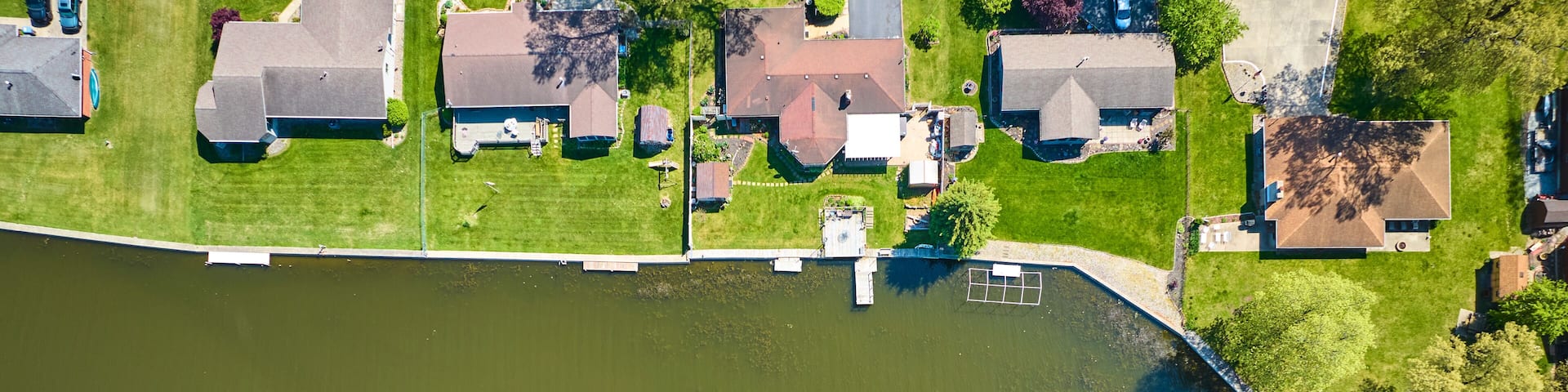 An aerial view of a residential area with houses, a river, and a dock.
