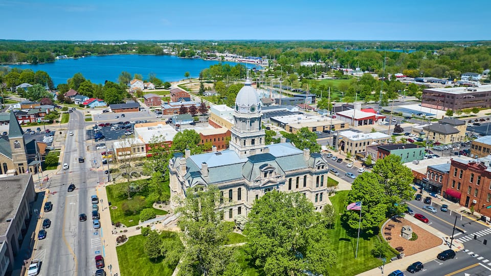 A town with a prominent clock tower, a large body of water, and a mix of commercial and residential buildings.