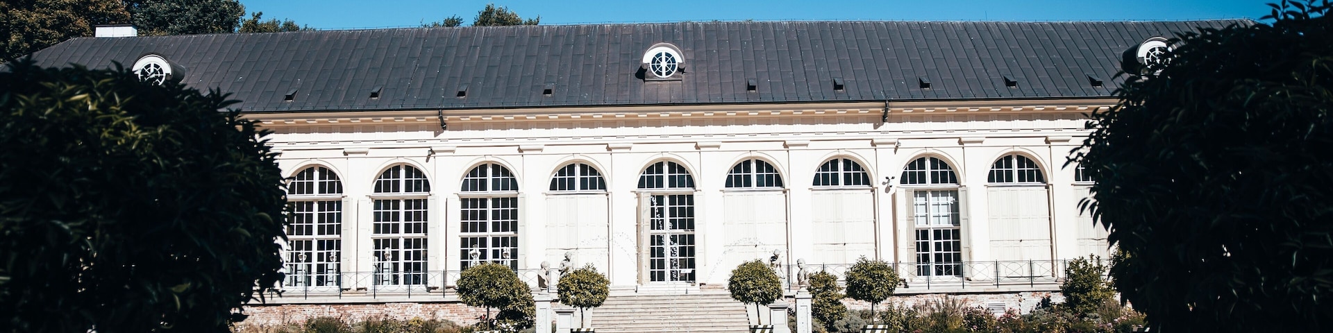Um edifício clássico com fachada simétrica, janelas em arco e entrada central.