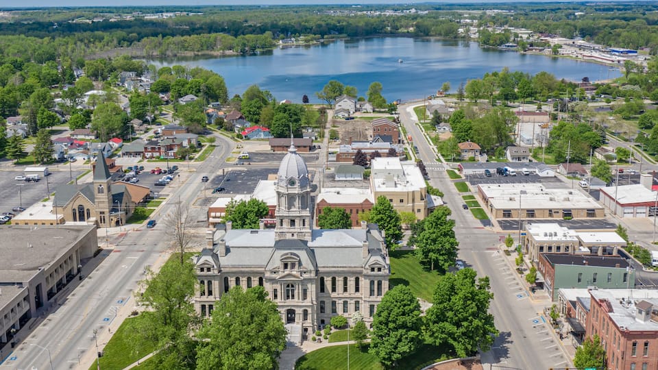 A town with a prominent historic building, a large lake, and surrounding greenery.