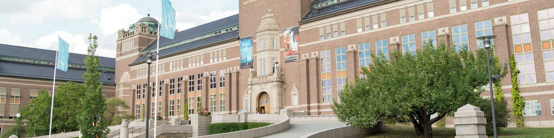 A large brick building with a dome and multiple flags.