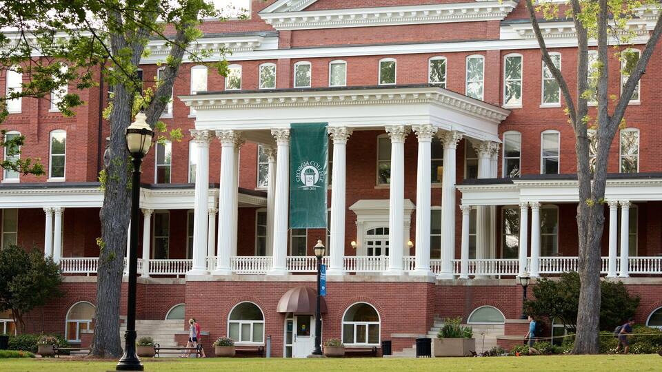 A Georgian architectural building with a red brick facade, white columns, and a green banner.