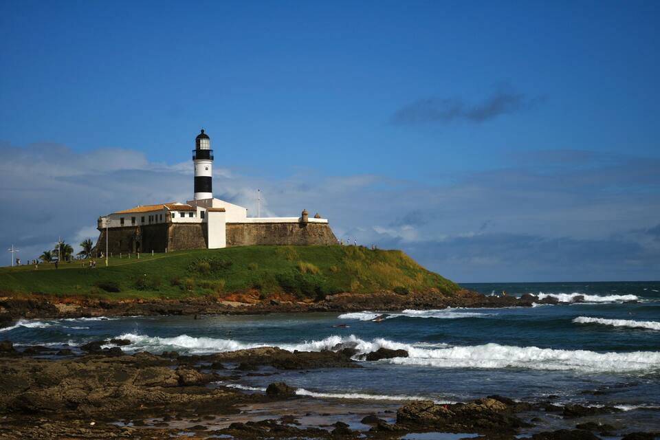 Um farol numa colina gramada junto ao mar.