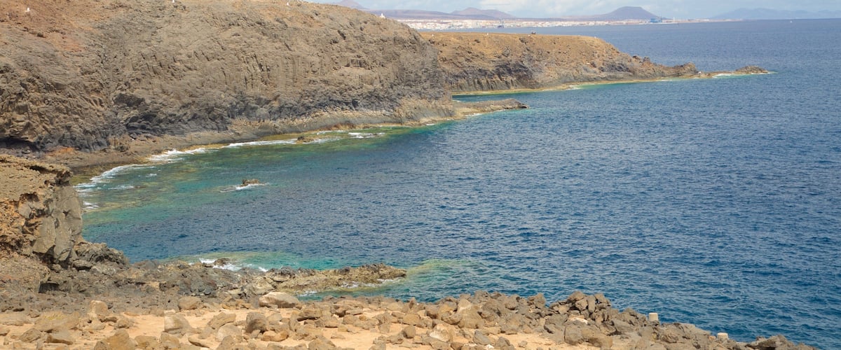 A coastal landscape with rocky cliffs and clear blue waters.
