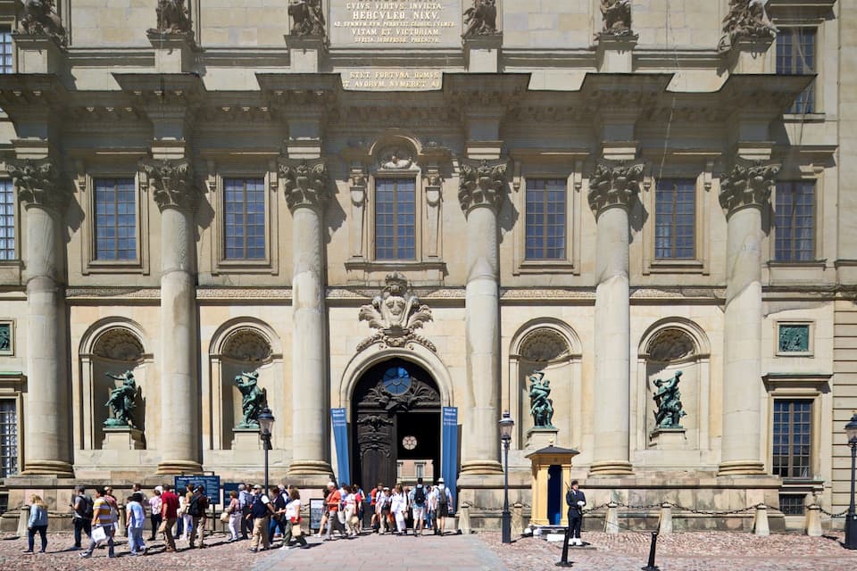 Un edificio histórico con arquitectura clásica, que presenta columnas, estatuas y una entrada muy ornamentada.