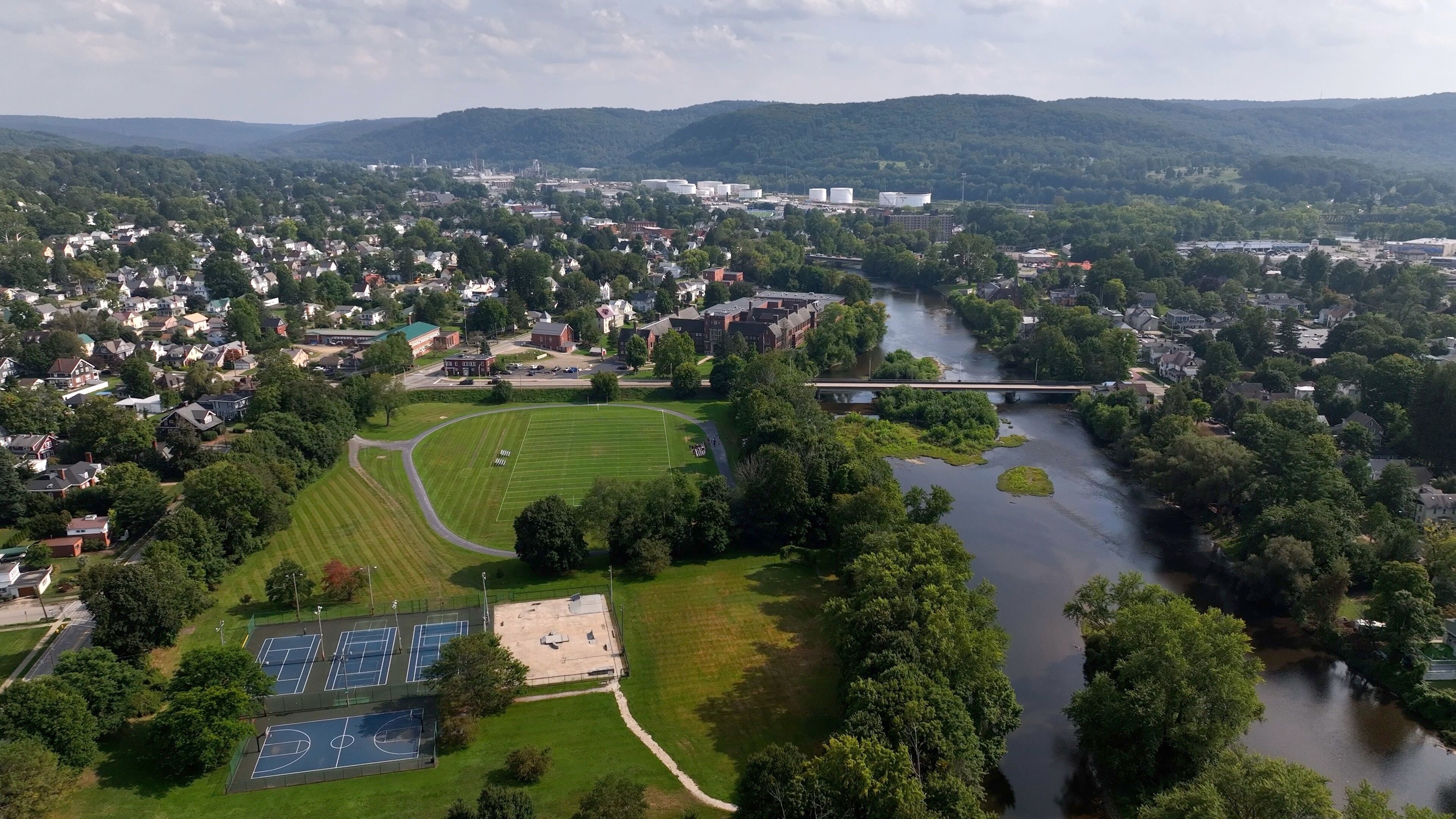 An aerial view of a town with a river, green fields, and a bridge.