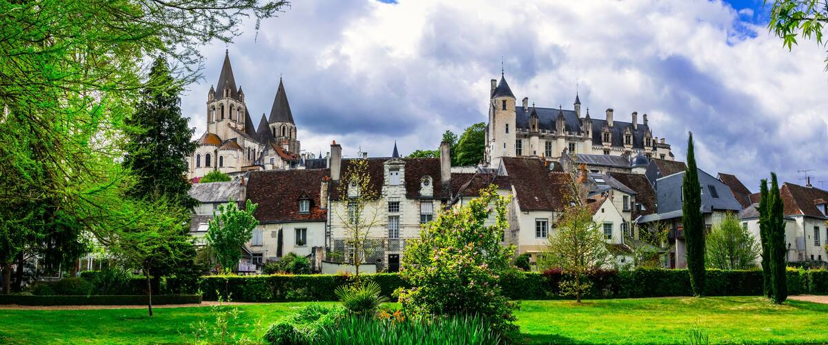 A historic castle with multiple towers and a well-maintained garden with a pond.