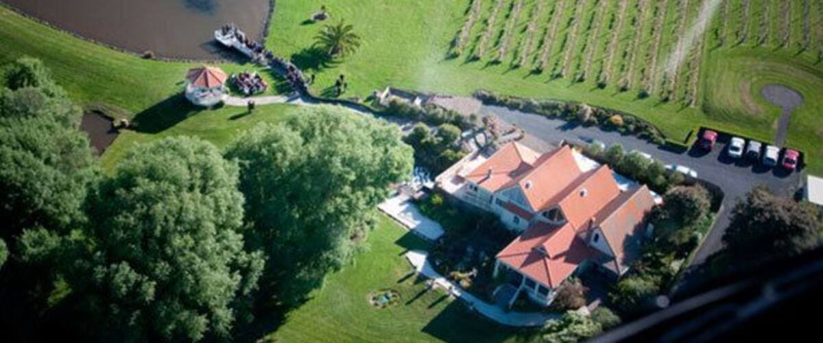 An aerial view of a property with a large house, a pond, and a well-maintained lawn.