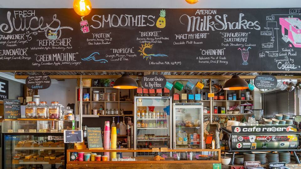 A coffee shop with a chalkboard menu listing various drinks and a coffee machine.