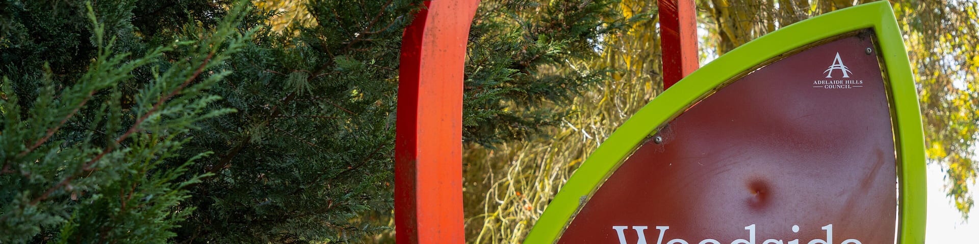 A sign for Adelaide Hills Council, established in 1851, with a logo and a depiction of a wine bottle and cup.