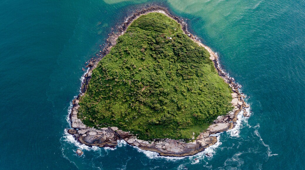 Aerial view of a triangular-shaped island in green sea (Batuta Island, Imbituba, Brazil)