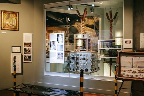 Une exposition présentant du matériel scientifique, des œuvres d’art encadrées et des panneaux d’information.