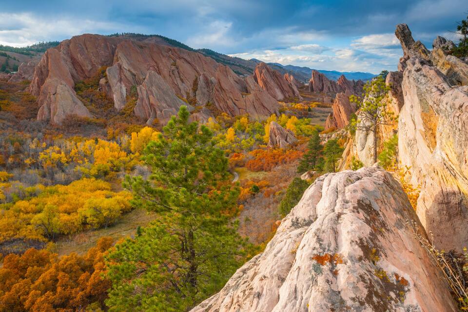 A mountainous landscape with autumn-colored trees and rocky formations.