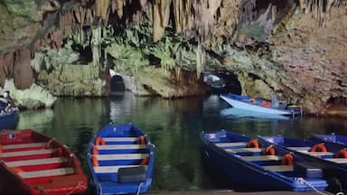 Una cueva con estalactitas y una fila de barcos amarrados en la entrada.