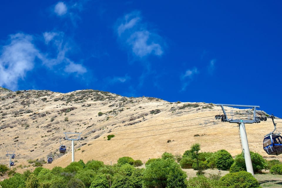 A cable car system on a mountain with clear blue skies.