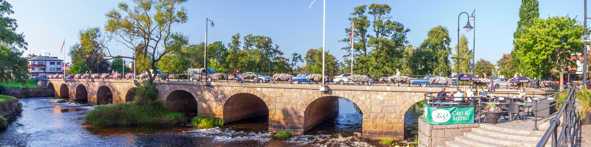 A stone bridge over a river with cars and pedestrians.