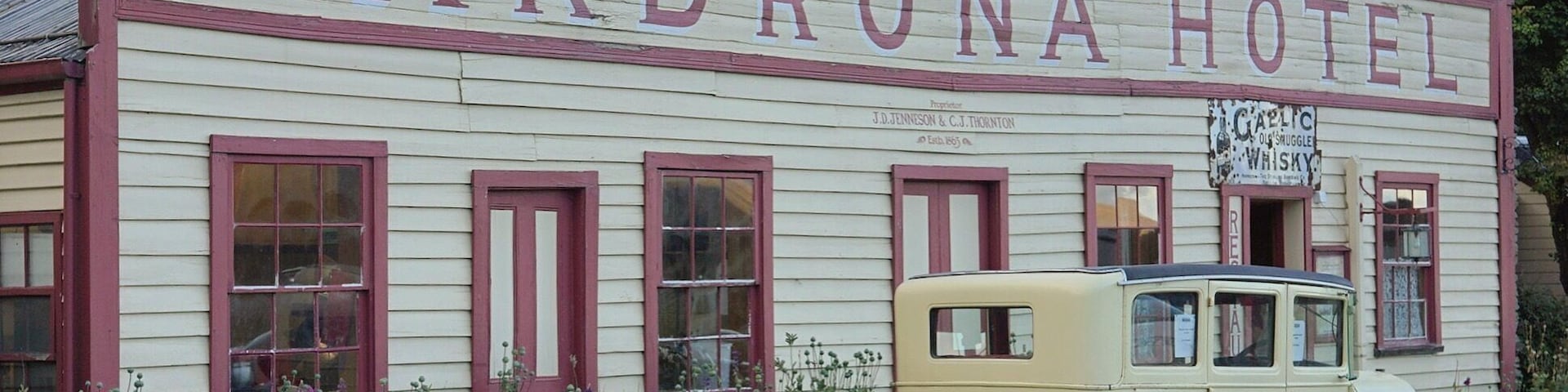 El exterior del Hotel Cardrona con un coche clásico estacionado al frente.