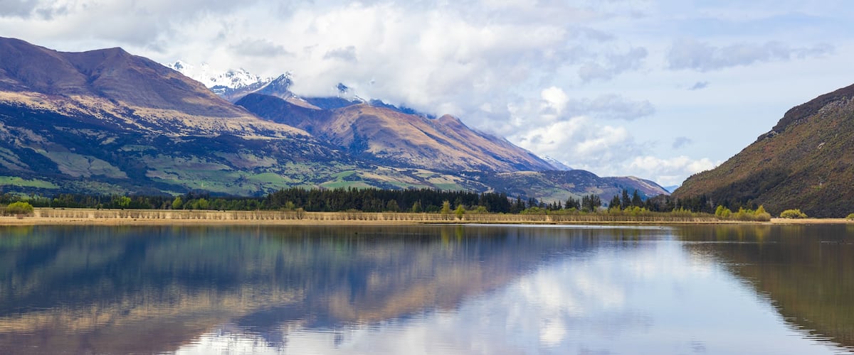 A calm lake with mountains in the background.