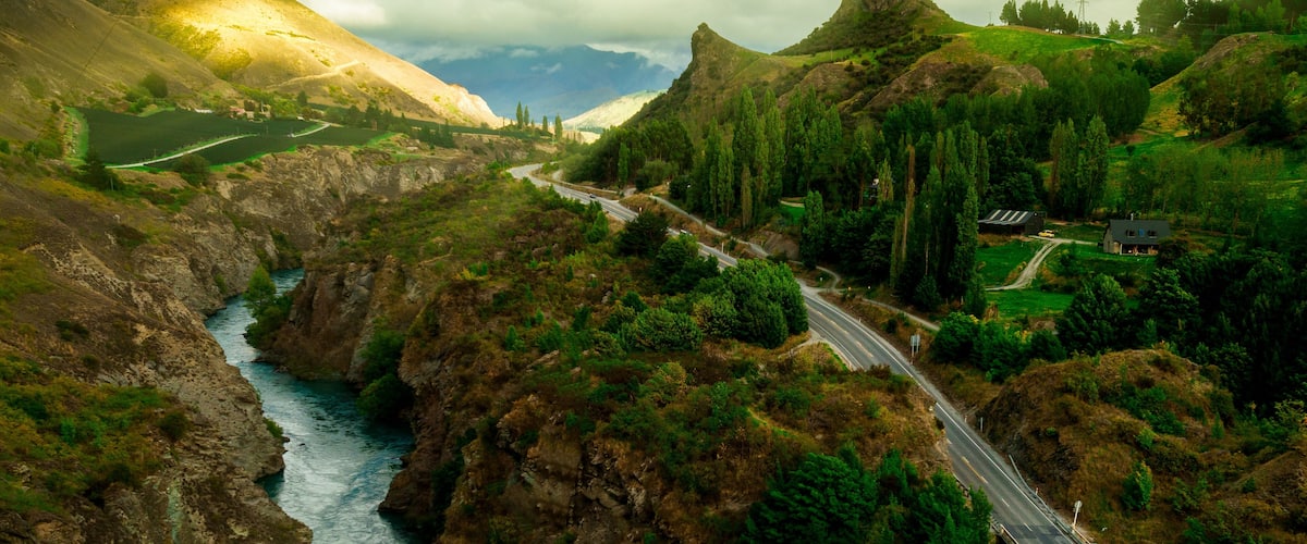 A river flowing through a mountainous valley with a bridge and a road.