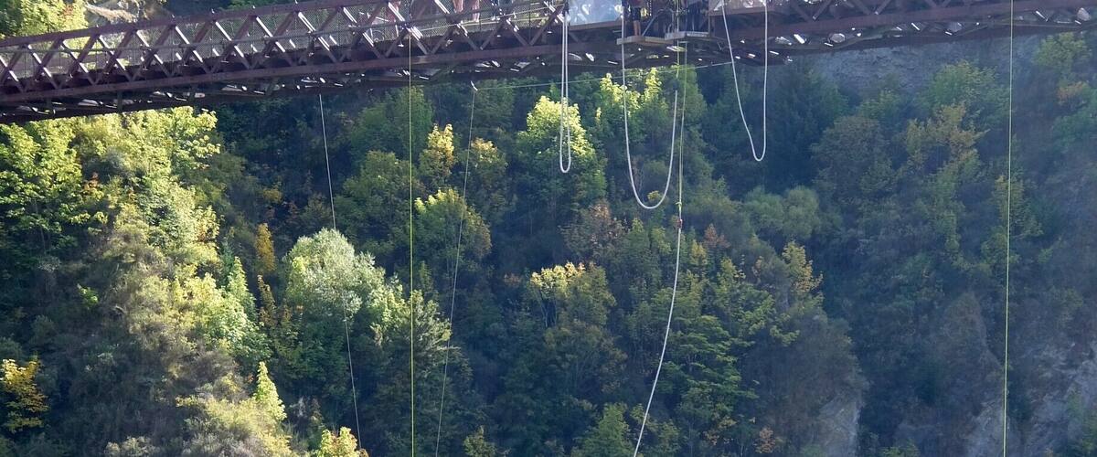 A bungee jumping platform with a bridge, a river, and a forested cliff.