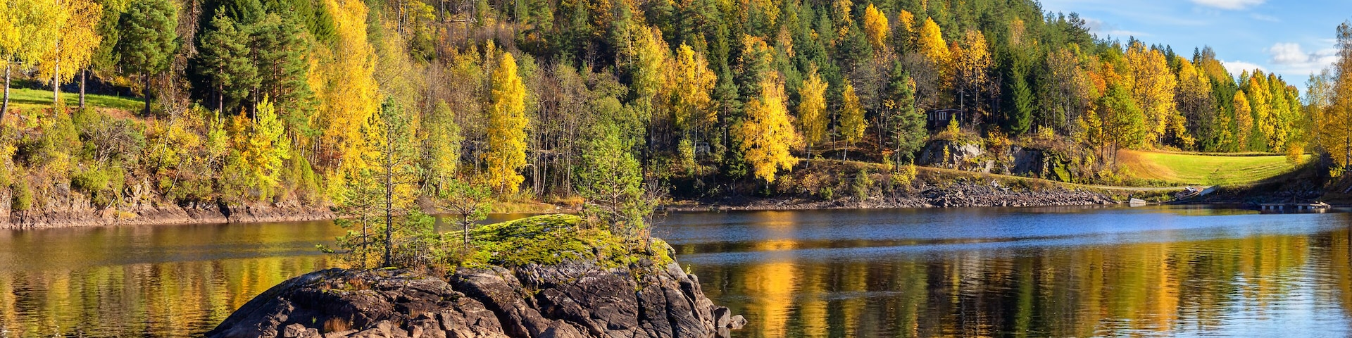 Panorama landscape of gold colorful fall time by the lake Tokke in Telemark region. Blue sky with white clouds . Nice reflections of little stone island in lake water. Autumn in Norway.