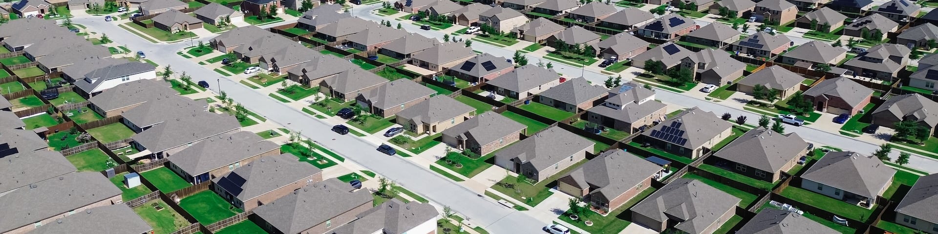 A residential area with houses, roads, and a large water tower in the distance.