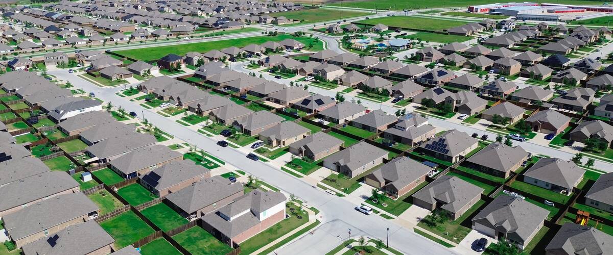 A residential area with houses, roads, and a large water tower in the distance.