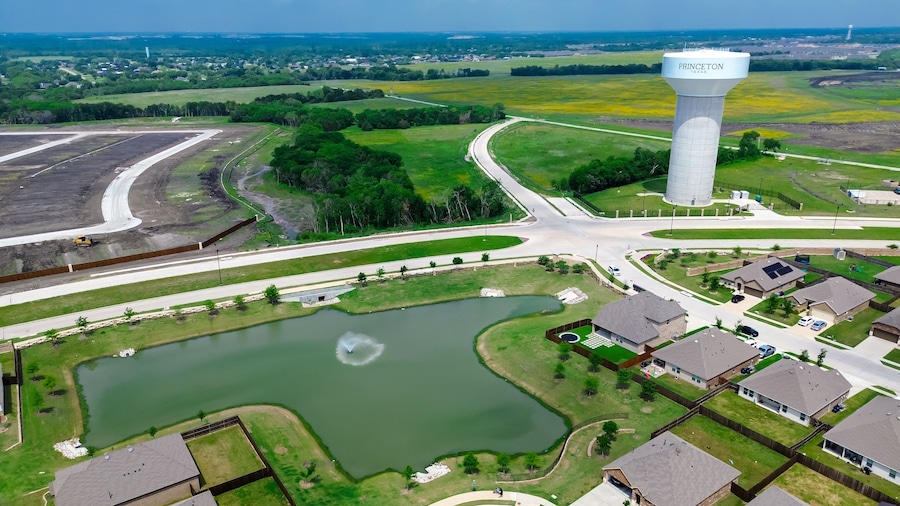 Lakeside two story houses with fountain, water tower along Myrick Lane in Princeton, Texas, slab foundation site preparing, upscale solar roofing on new construction home large backyard, aerial