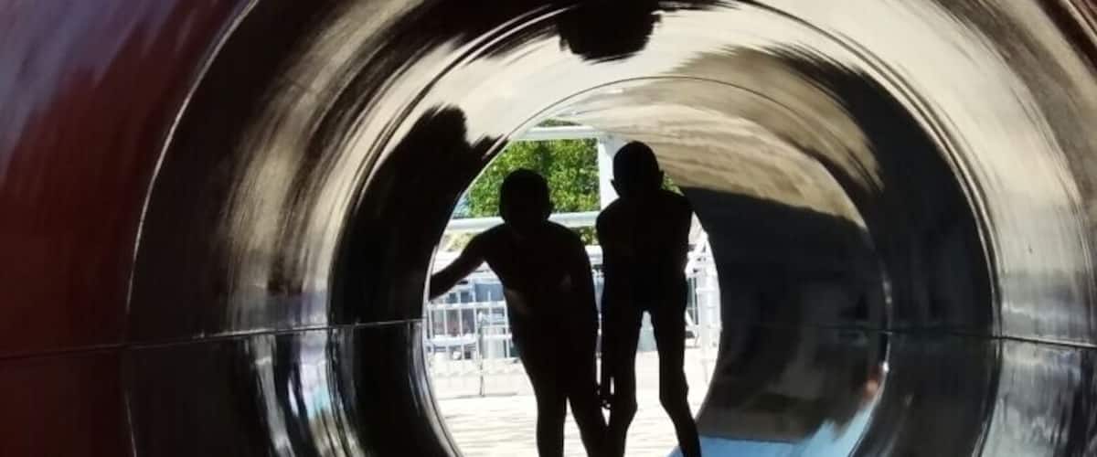A metallic tunnel with two people silhouetted inside.