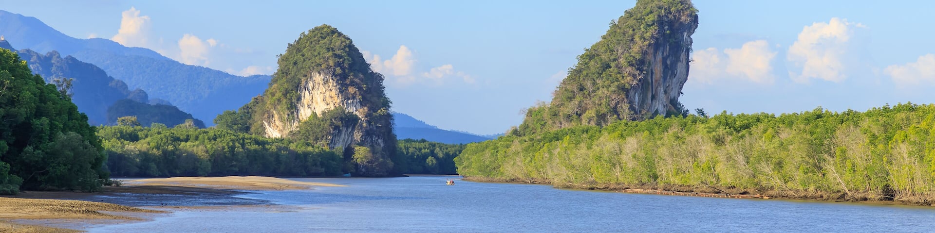A river flanked by lush green hills and two prominent limestone cliffs.