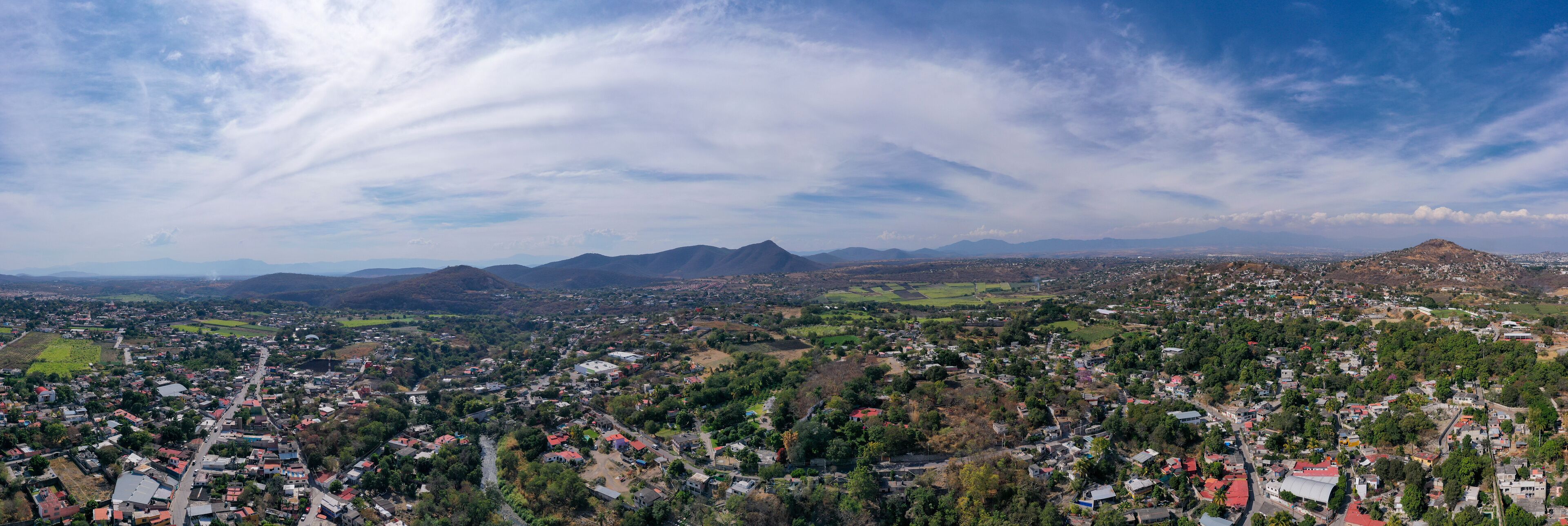 A panoramic view of a town nestled in a valley with mountains in the background.