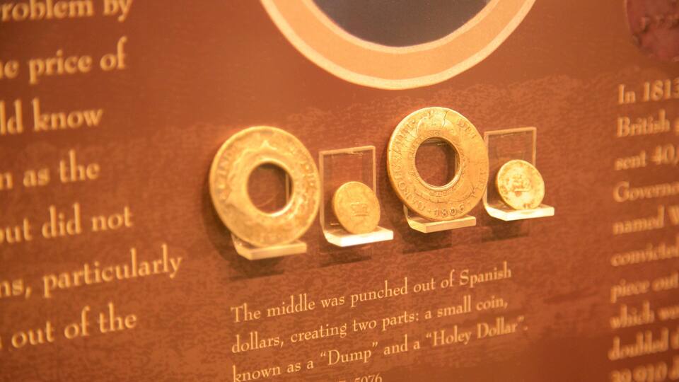A display of historical coins with inscriptions and a plaque providing context.