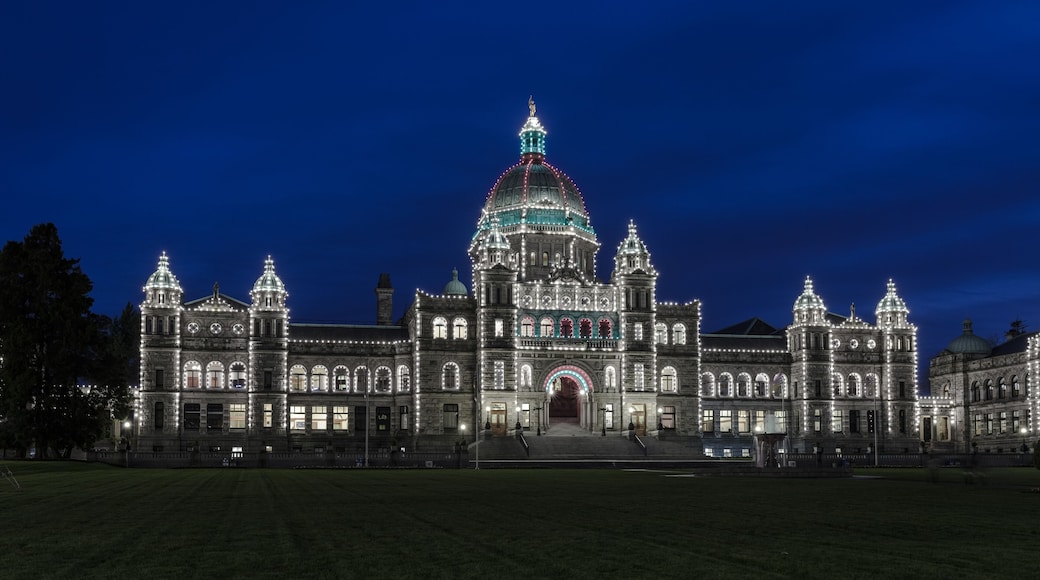 A large, illuminated building with a prominent dome and multiple towers, surrounded by a well-maintained lawn.