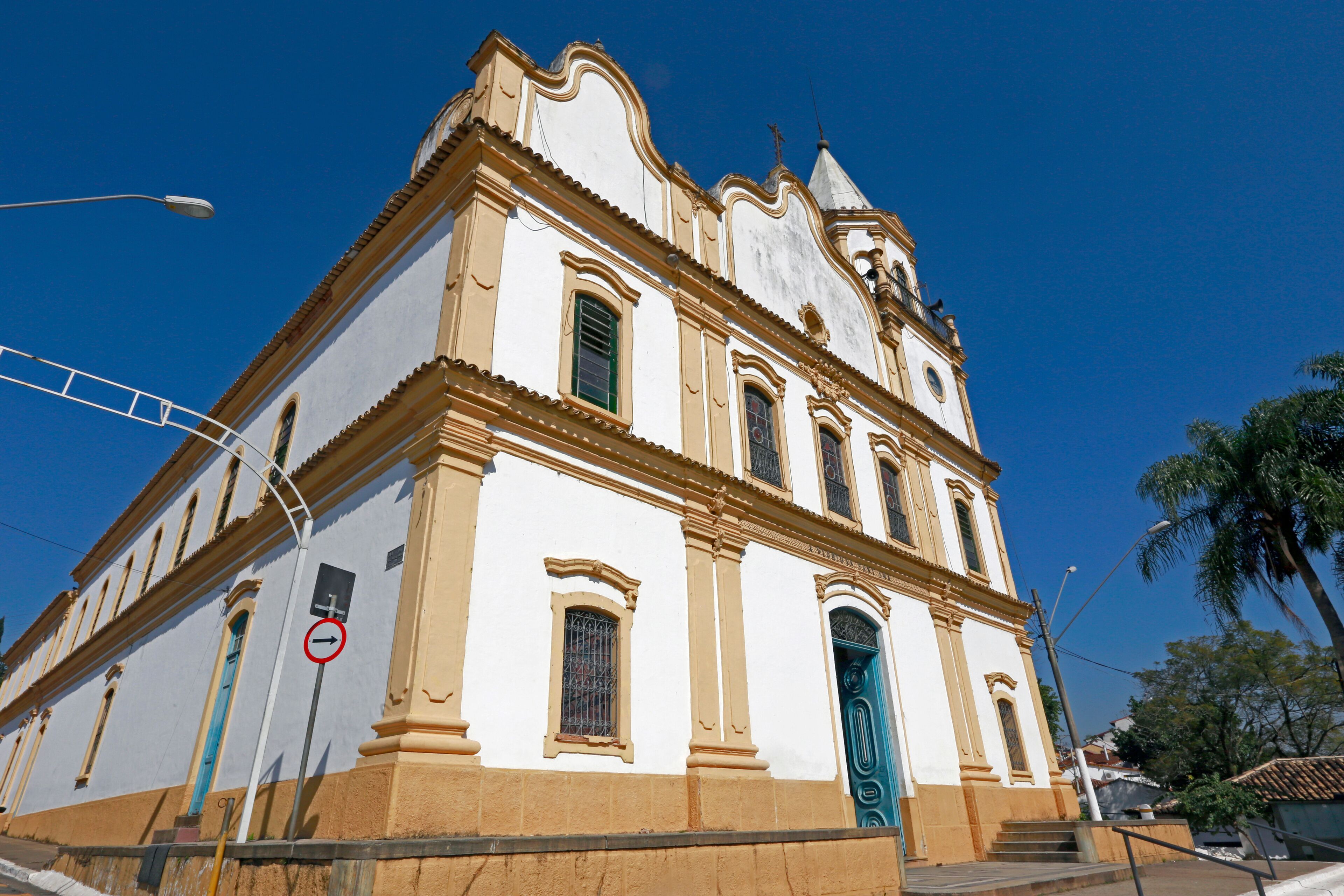 A historic church with a white facade and a blue door, set against a clear blue sky.