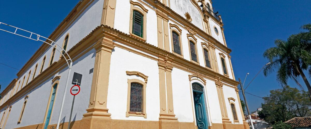 A historic church with a white facade and a blue door, set against a clear blue sky.